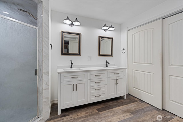 full bathroom with a stall shower, a sink, and wood finished floors