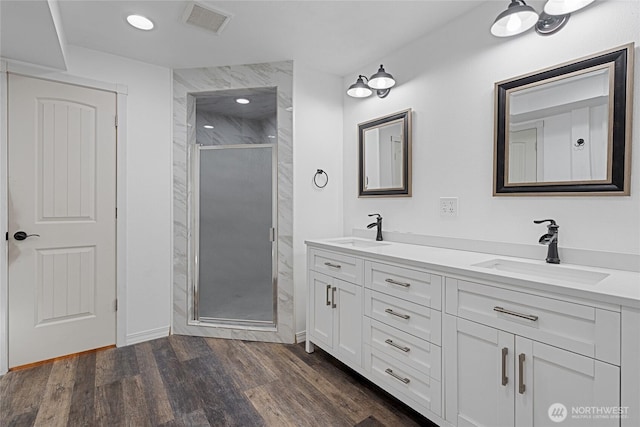 full bath featuring a shower stall, visible vents, a sink, and wood finished floors