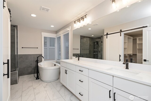 bathroom featuring marble finish floor, double vanity, visible vents, a sink, and a shower stall