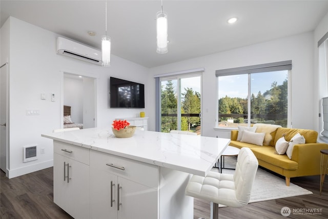 kitchen featuring pendant lighting, visible vents, dark wood-type flooring, open floor plan, and a wall mounted air conditioner