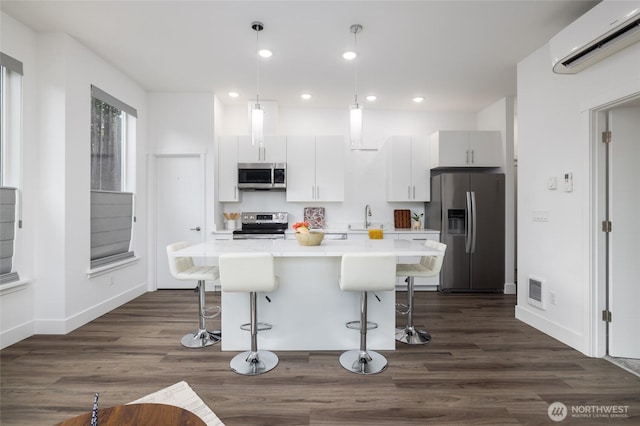 kitchen with a kitchen island, a breakfast bar, stainless steel appliances, a sink, and a wall mounted AC