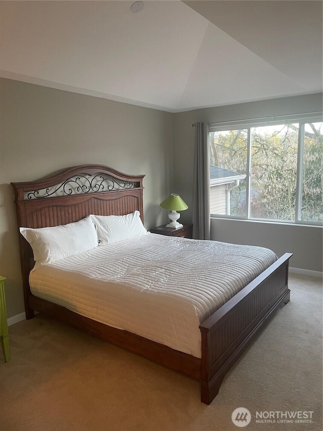 bedroom featuring light carpet, baseboards, and vaulted ceiling