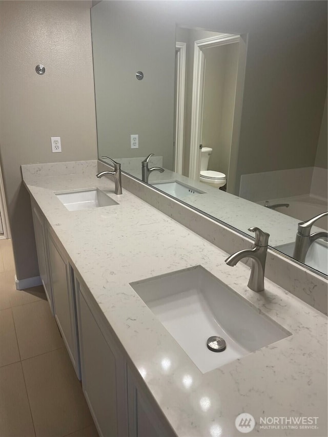 full bath featuring a sink, toilet, and double vanity