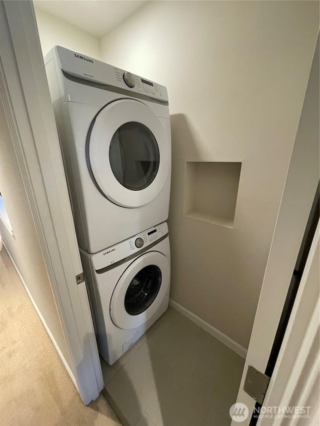 washroom with laundry area, baseboards, and stacked washer and clothes dryer