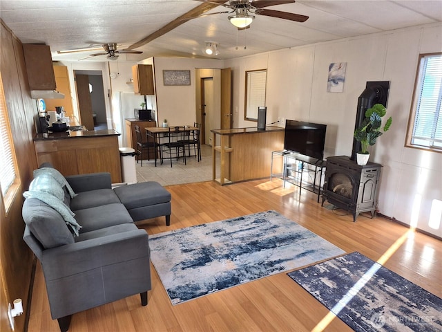 living room featuring a wood stove, light wood finished floors, and a ceiling fan