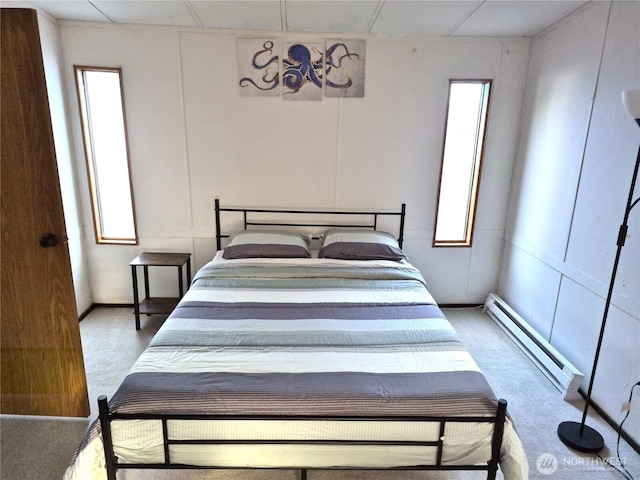 carpeted bedroom with a baseboard heating unit and multiple windows