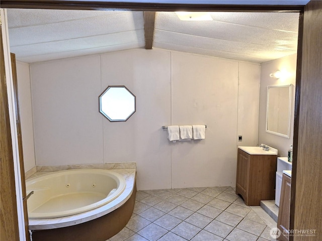 full bath with a tub with jets, tile patterned floors, vaulted ceiling, a textured ceiling, and vanity