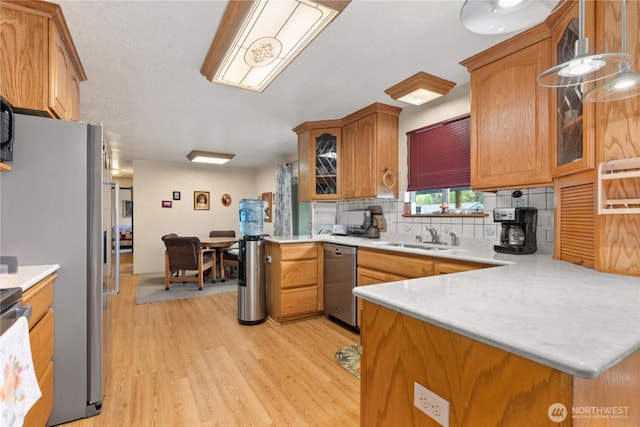 kitchen featuring tasteful backsplash, stainless steel dishwasher, a sink, light countertops, and light wood-style floors