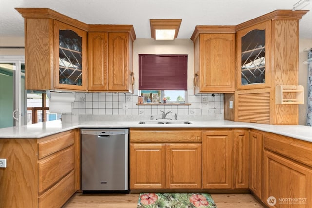 kitchen with a sink, tasteful backsplash, stainless steel dishwasher, and light wood finished floors