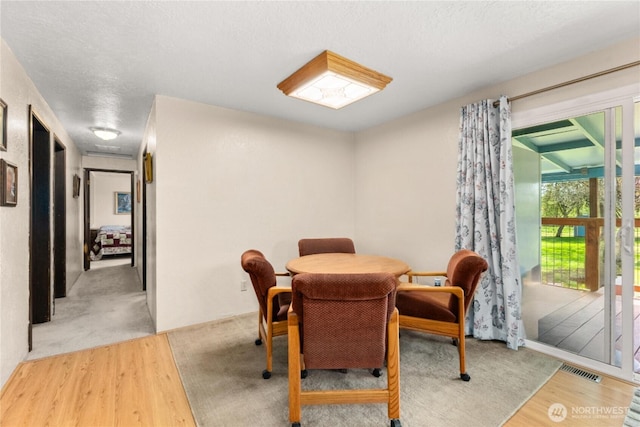 dining area featuring visible vents, a textured ceiling, and wood finished floors