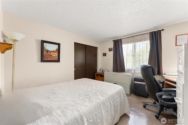 bedroom with a textured ceiling, light colored carpet, and a closet