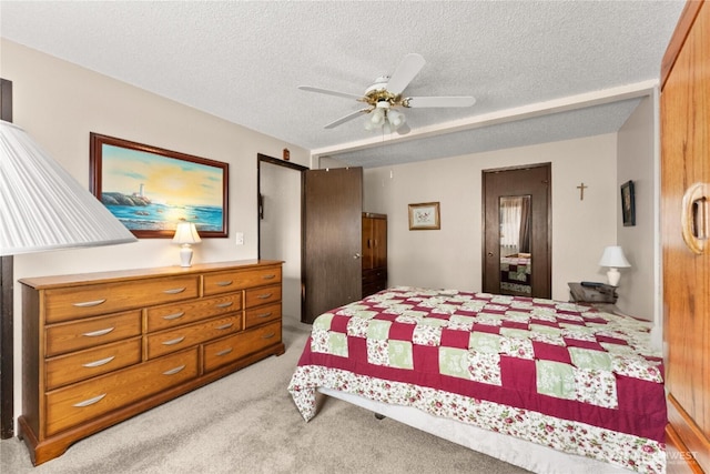 bedroom with a textured ceiling, light colored carpet, and ceiling fan