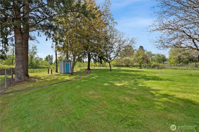 view of yard with fence, a storage unit, and an outdoor structure