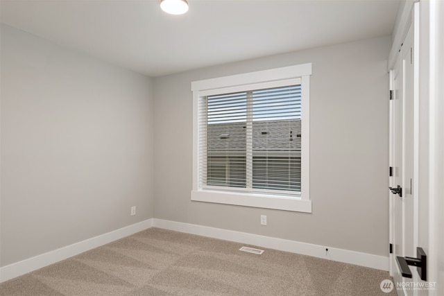 empty room featuring light carpet, visible vents, and baseboards