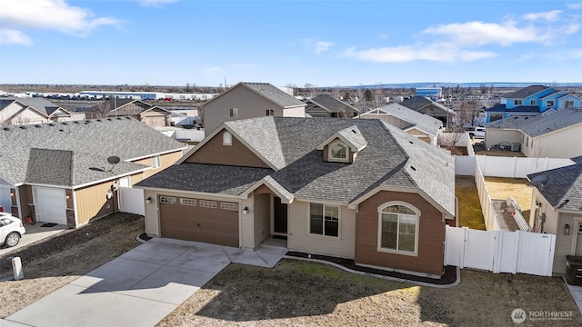 view of front facade featuring roof with shingles, fence, a garage, a residential view, and driveway