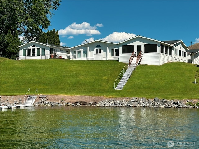 back of house with a yard and a water view