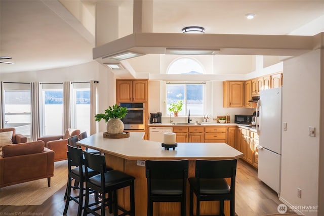 kitchen with open floor plan, light countertops, white appliances, and a kitchen bar