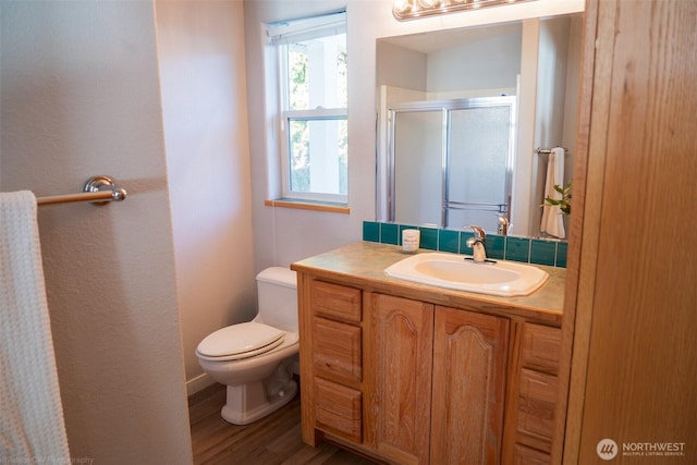 bathroom with toilet, a stall shower, wood finished floors, and vanity