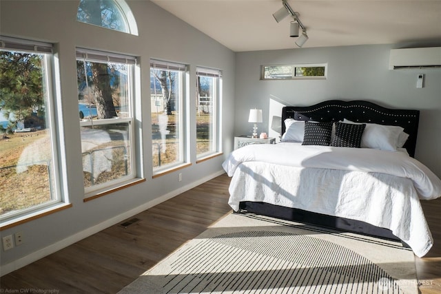 bedroom with wood finished floors, visible vents, baseboards, vaulted ceiling, and a wall mounted AC