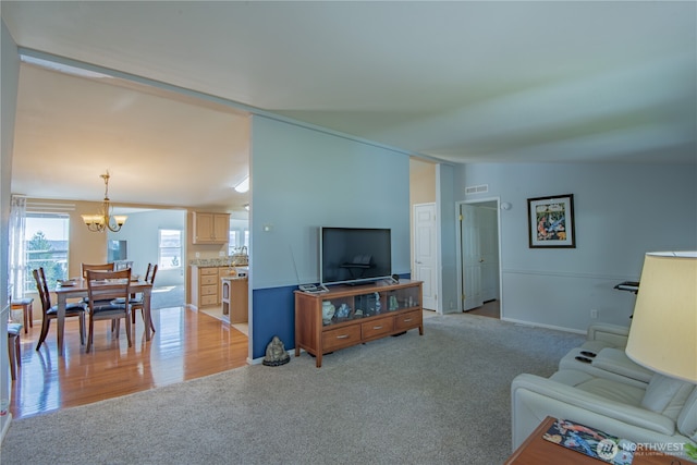 living room featuring visible vents, a chandelier, vaulted ceiling, and light colored carpet