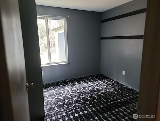 unfurnished room featuring a healthy amount of sunlight and dark carpet