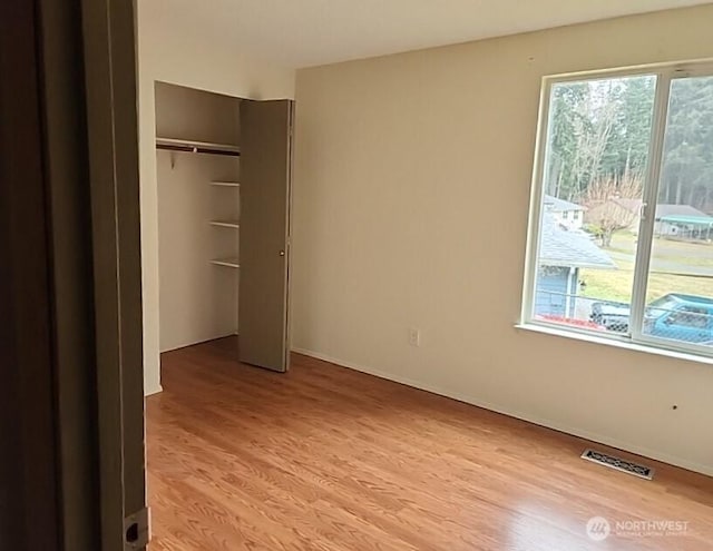 unfurnished bedroom featuring multiple windows, visible vents, and light wood-style floors