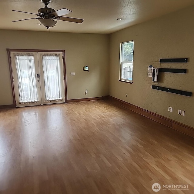 unfurnished room with a ceiling fan, baseboards, wood finished floors, and french doors