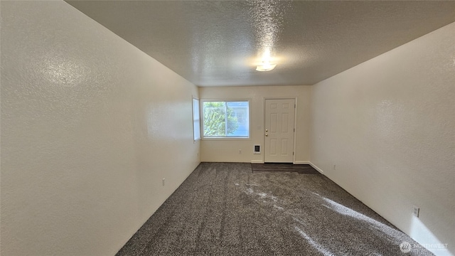 spare room featuring carpet, a textured wall, and a textured ceiling