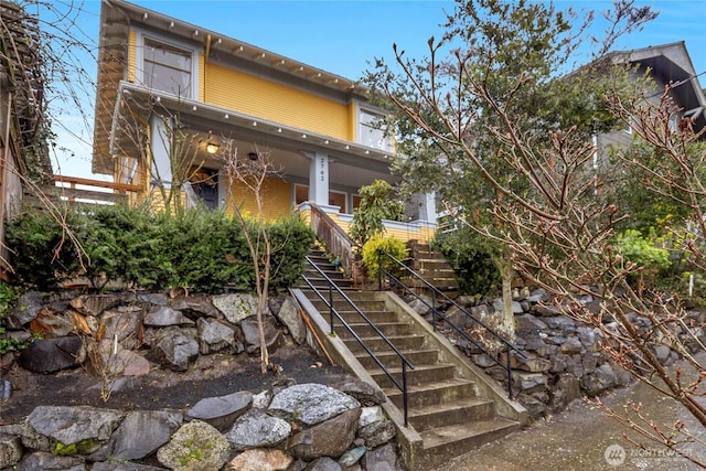 back of property with covered porch and stairs