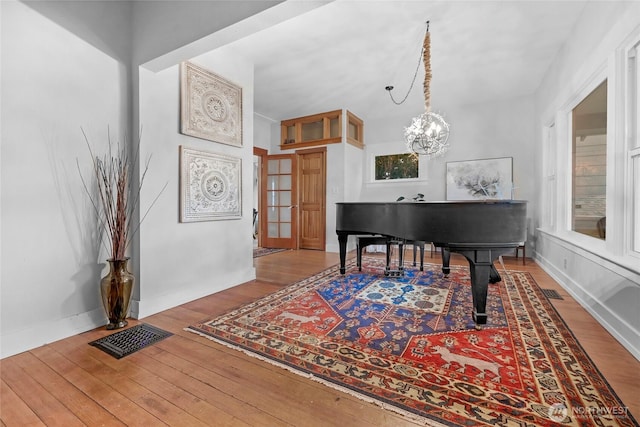 interior space with hardwood / wood-style floors, a notable chandelier, baseboards, and visible vents