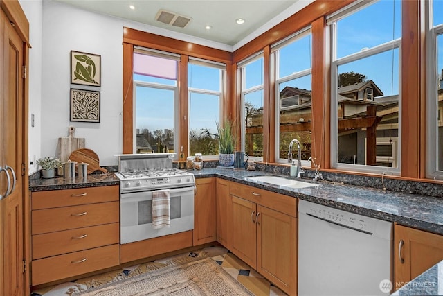 kitchen featuring white appliances, dark stone countertops, visible vents, recessed lighting, and a sink