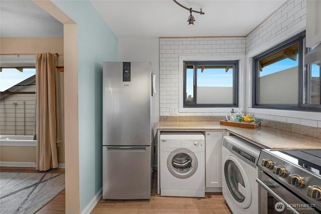 laundry room with washing machine and clothes dryer, laundry area, and light wood finished floors