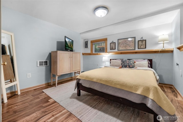 bedroom with visible vents, baseboards, and wood finished floors