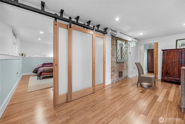 interior space with recessed lighting, a barn door, baseboards, and light wood finished floors