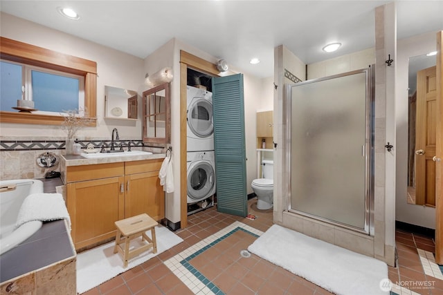 bathroom featuring tile patterned floors, a shower stall, and stacked washer / dryer