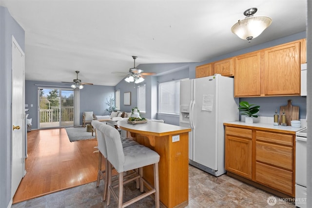 kitchen with white appliances, lofted ceiling, light countertops, a kitchen bar, and open floor plan