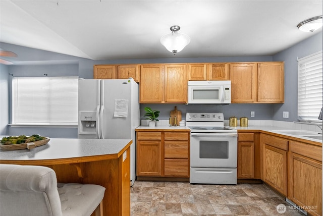 kitchen with white appliances, light countertops, a kitchen breakfast bar, and a sink