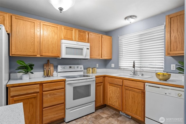 kitchen with white appliances, light countertops, visible vents, and a sink