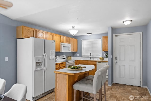 kitchen with a center island, light countertops, a kitchen breakfast bar, white appliances, and a sink