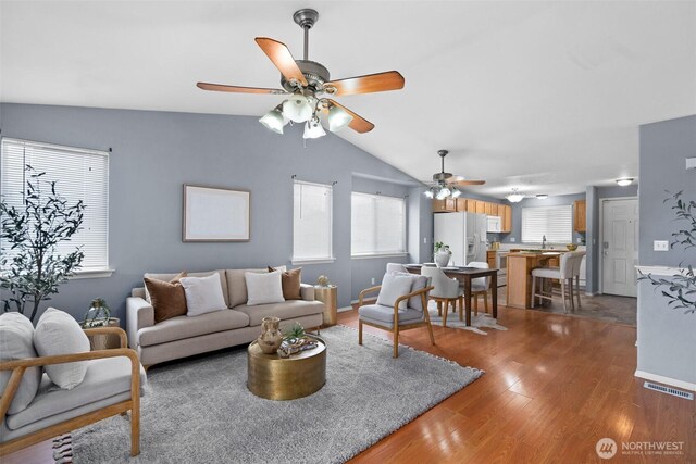 living room with visible vents, wood finished floors, a ceiling fan, and vaulted ceiling