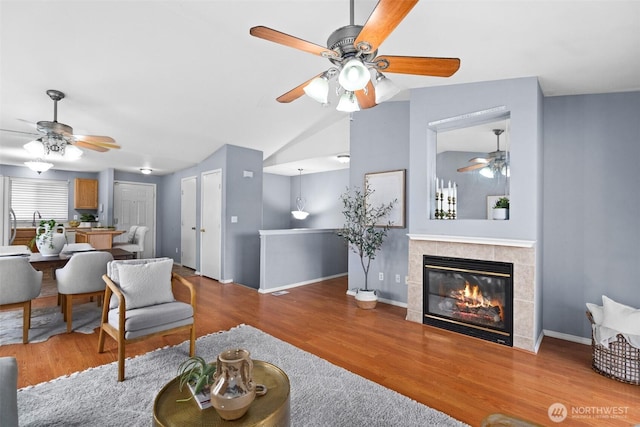 living room featuring baseboards, lofted ceiling, wood finished floors, and a fireplace