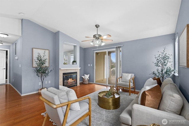 living room featuring baseboards, wood finished floors, a fireplace, and vaulted ceiling