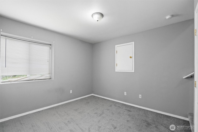 carpeted empty room featuring baseboards