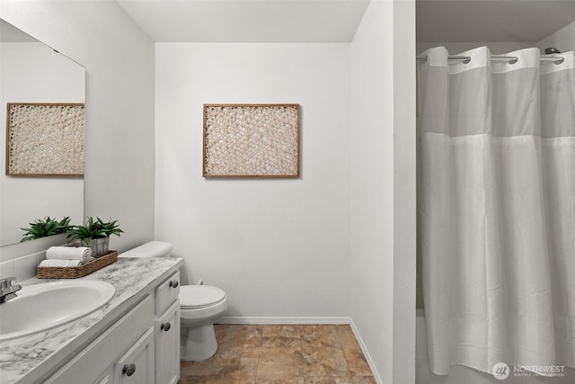 full bathroom featuring baseboards, toilet, shower / tub combo, stone finish floor, and vanity