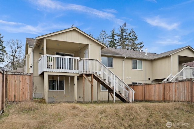 back of property with a deck, stairs, and fence