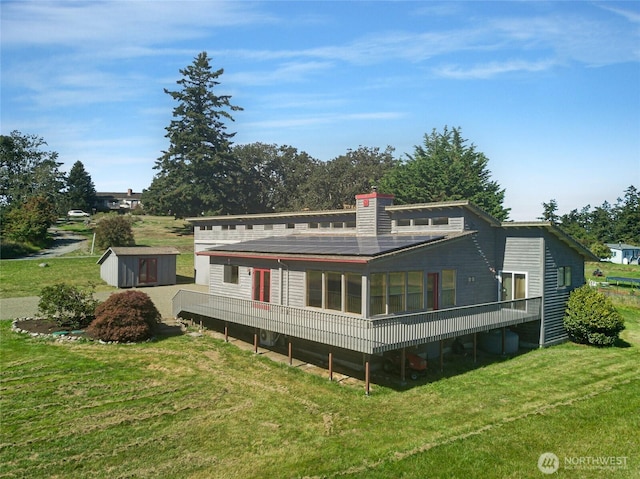 rear view of house featuring a storage shed, a lawn, an outdoor structure, and a sunroom