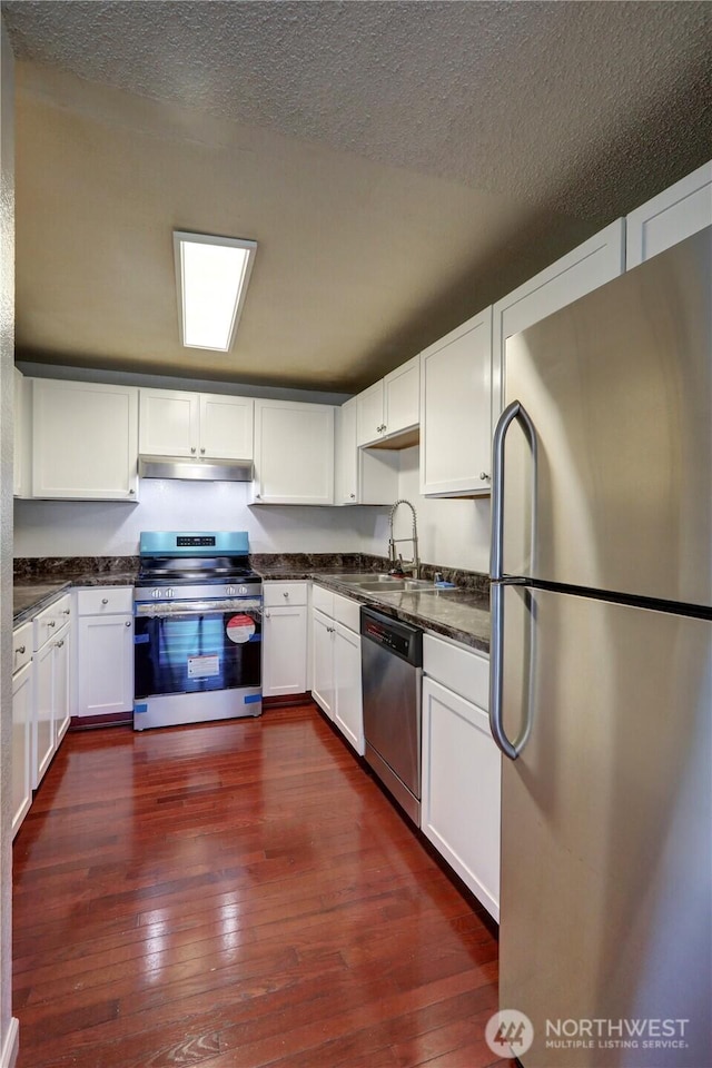 kitchen featuring stainless steel appliances, dark wood-style flooring, a sink, and under cabinet range hood