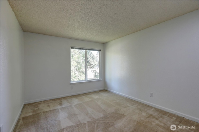 carpeted spare room featuring baseboards and a textured ceiling