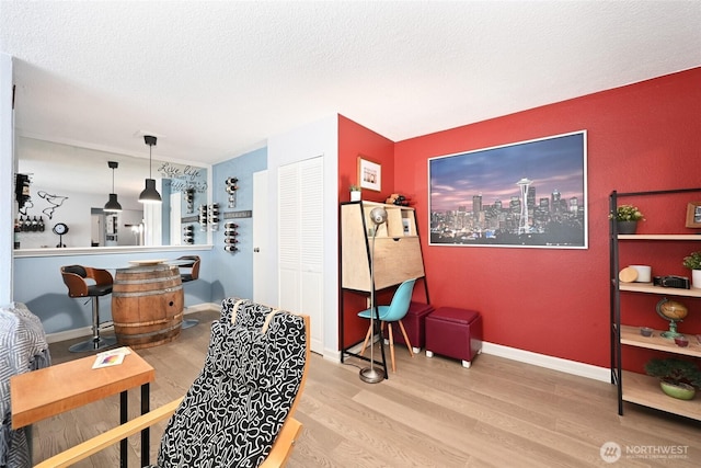 interior space with baseboards, a textured ceiling, and wood finished floors