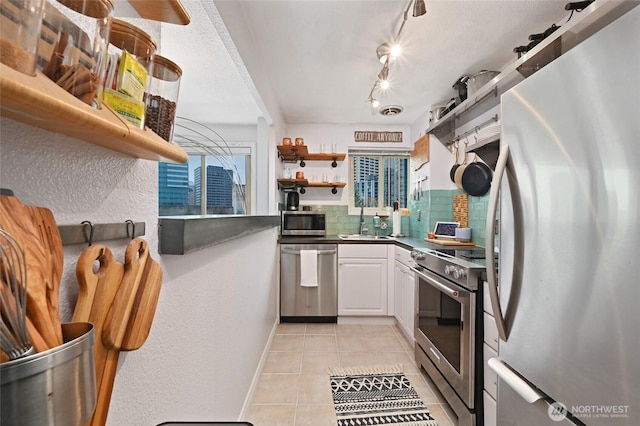 kitchen with open shelves, a sink, stainless steel appliances, white cabinetry, and backsplash